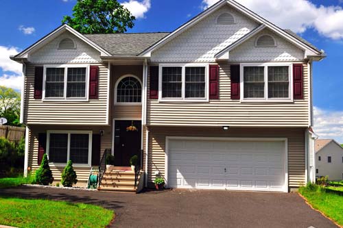 Front driveway view of home with beige siding and red window panels